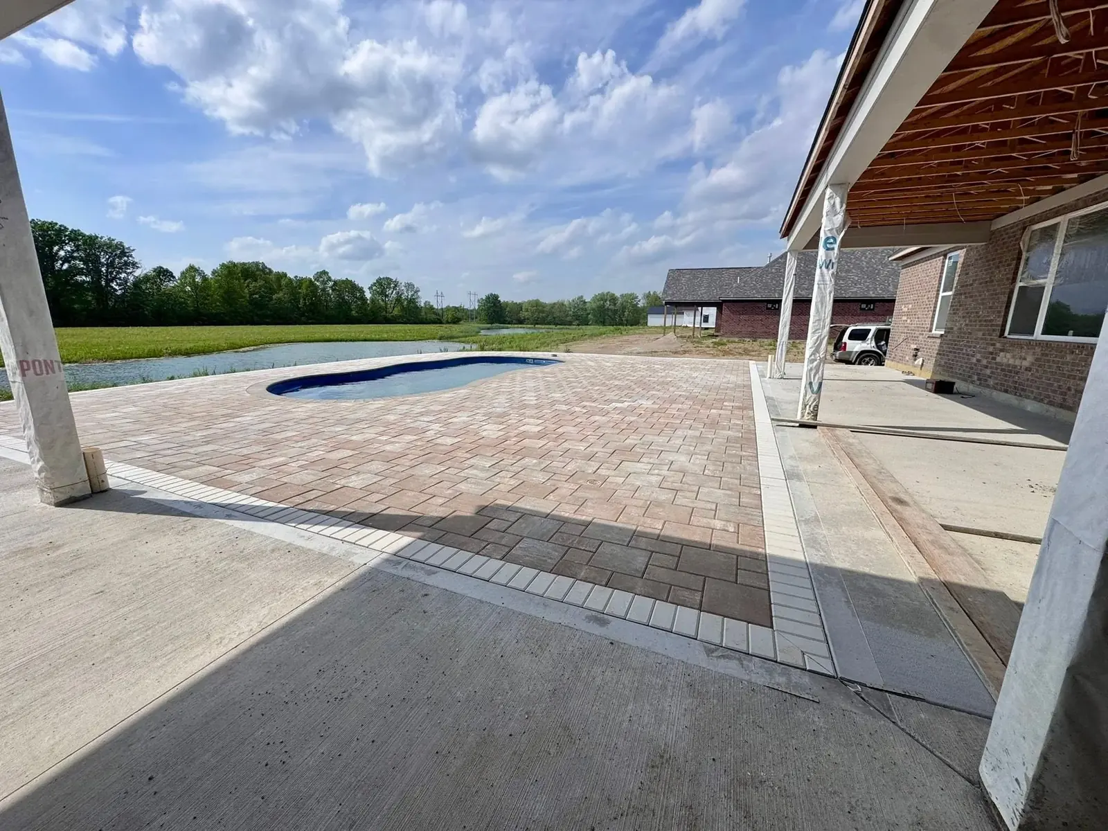 Custom paver patio under construction beside a new inground pool