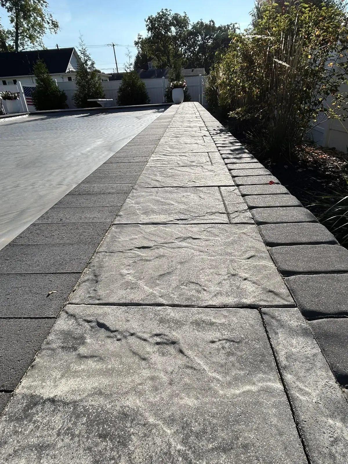 Paver walkway beside pool cover and vinyl fence