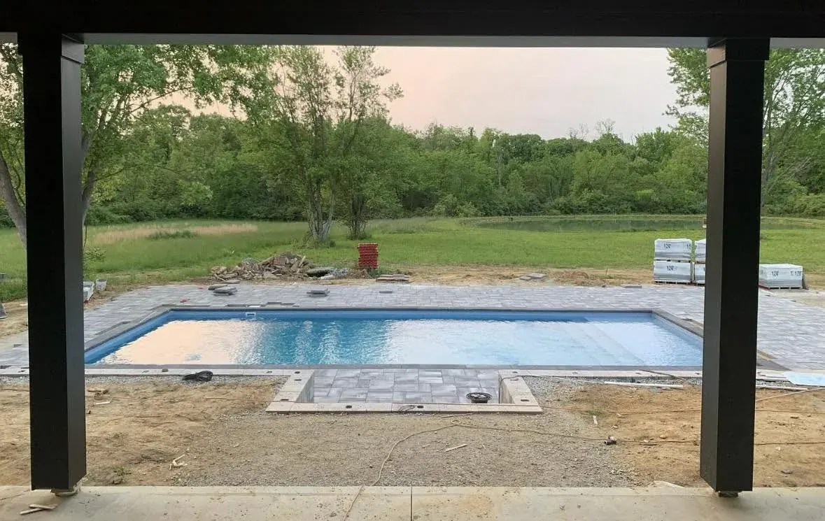 Rectangular pool viewed through a modern pergola at dusk